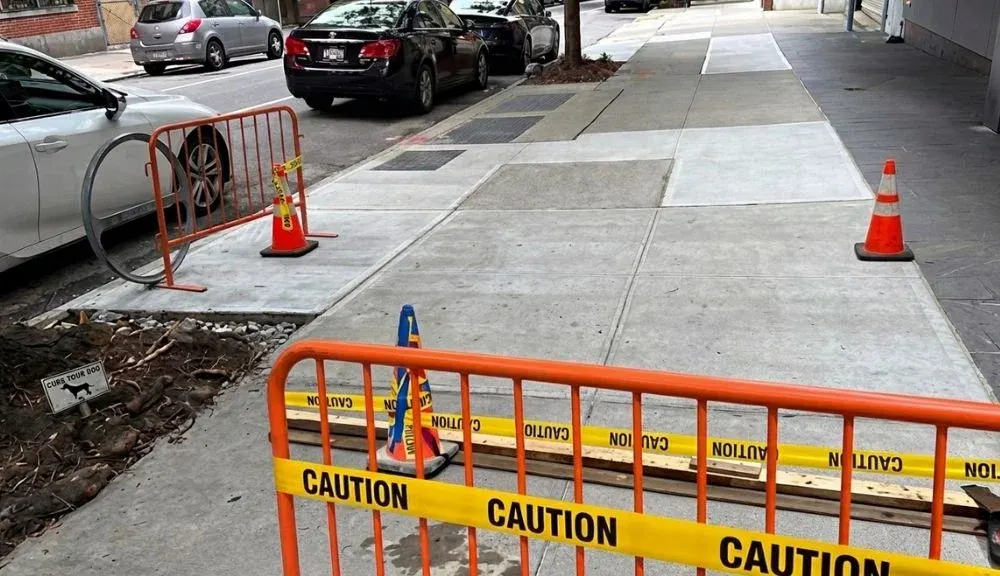 new concrete sidewalk with caution barriers after violation removal at 425 w 53rd st in manhattan