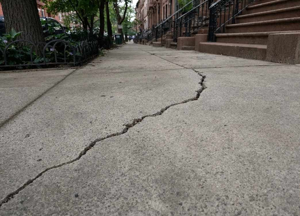 Cracked concrete sidewalk in New York City in need of repair